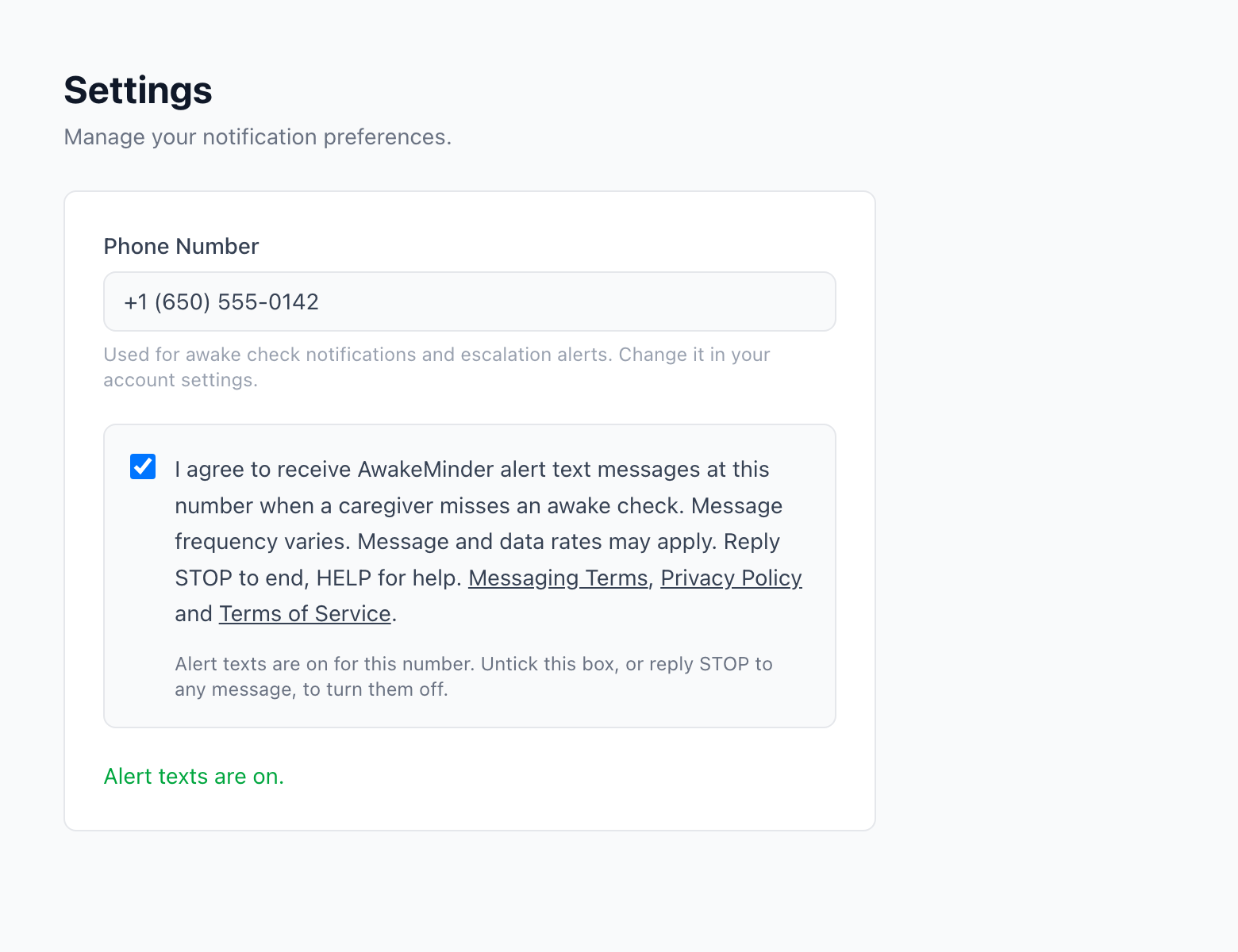 The same AwakeMinder settings screen after the user has ticked the consent box. The box is checked, a confirmation reading Settings saved appears, and the helper text now reads: Alert texts are on for this number. Untick this box, or reply STOP to any message, to turn them off.